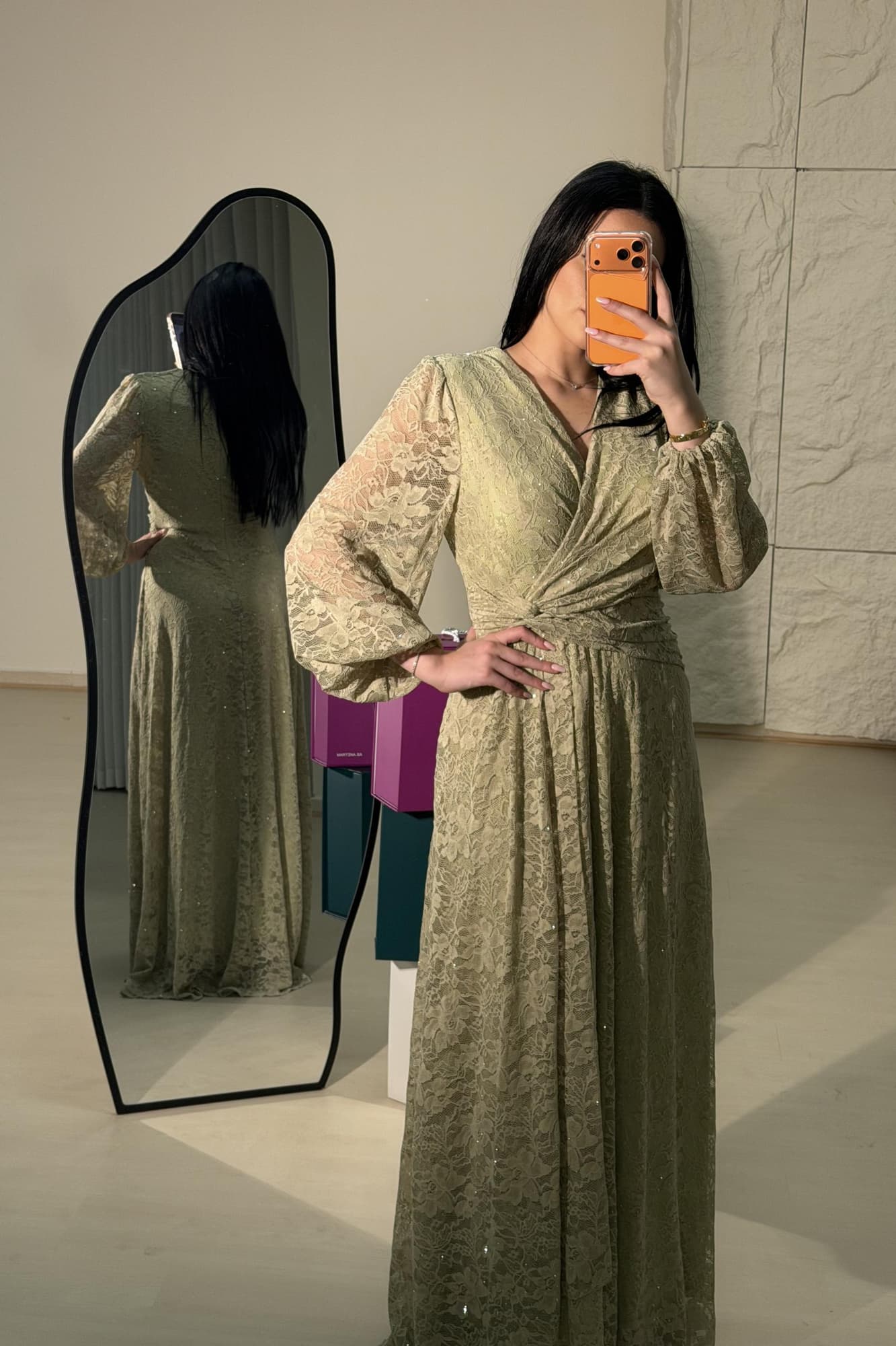 فستان طويل من الدانتيل بلون أخضر فاتح هادئ، يعكس أنوثة راقية ولمسة رومانسية ناعمة يتميّز بقصّة لفّ (Wrap) أنيقة مع عقدة جانبية تبرز الخصر