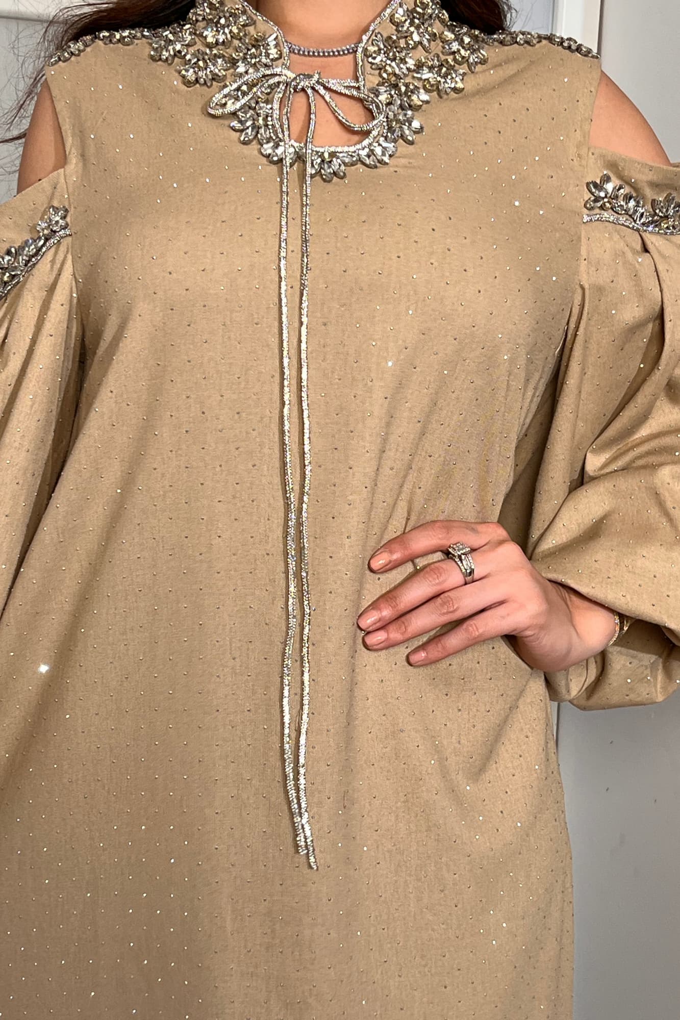 فستان طويل يتميّز بقصّة واسعة مريحة تنسدل بانسيابية أنثوية مع أكمام طويلة مفتوحة عند الكتفين تضيف لمسة عصرية راقية. بيج