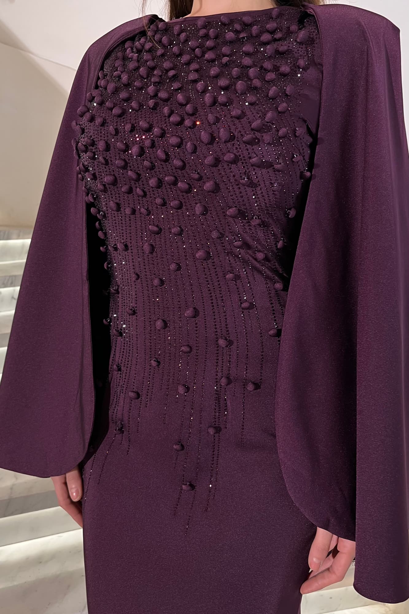 فستان سهرة راقٍ بقصّة مستقيمة تضفي طول وأناقة على الإطلالة مزين بتطريزات لامعة موف غامق