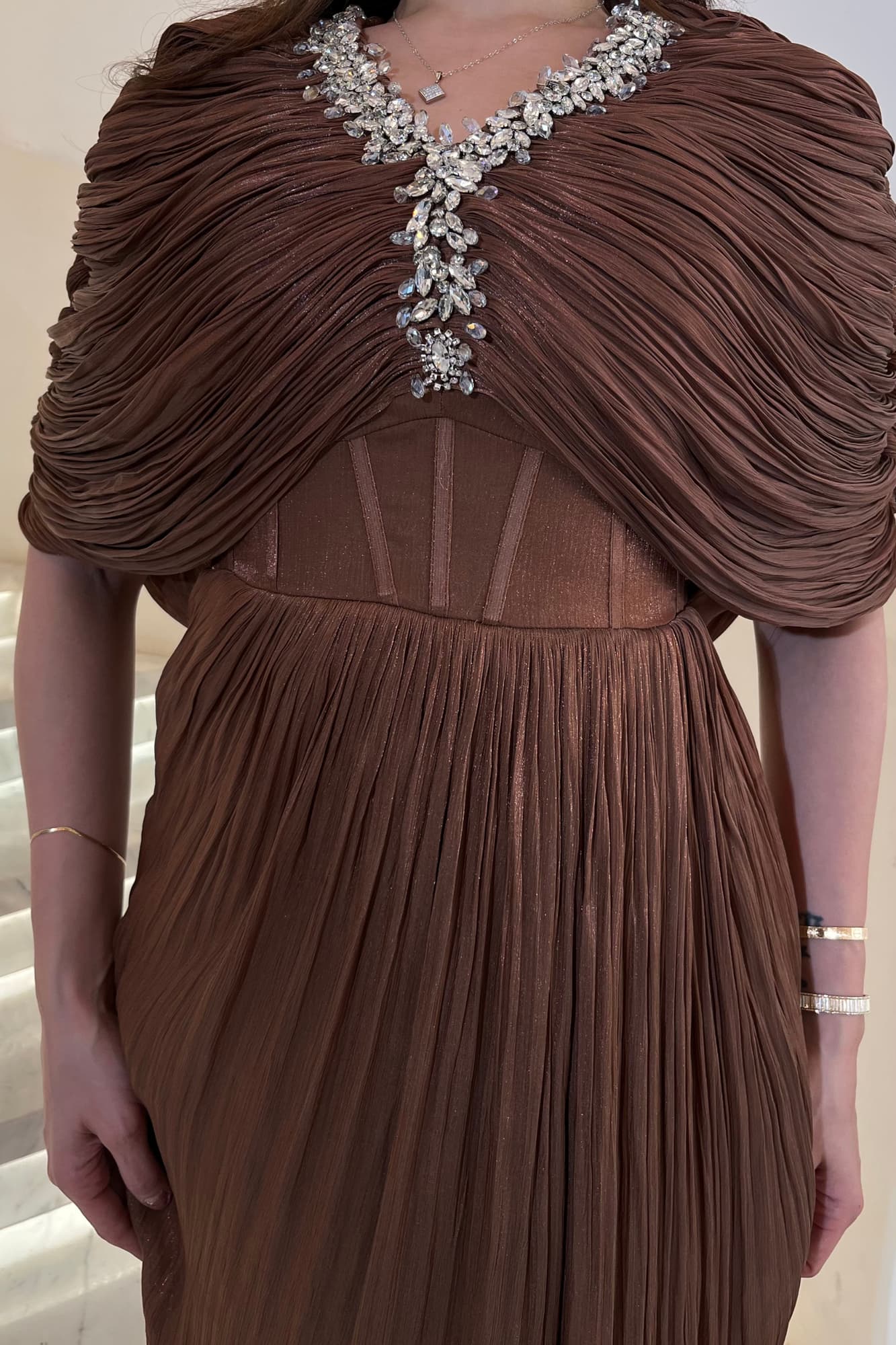 فستان سهرة يمنح إطلالة فاخرة وراقية مصنوع من قماش انسيابي خفيف بملمس ناعم وطيات حريرية متدرجة بني