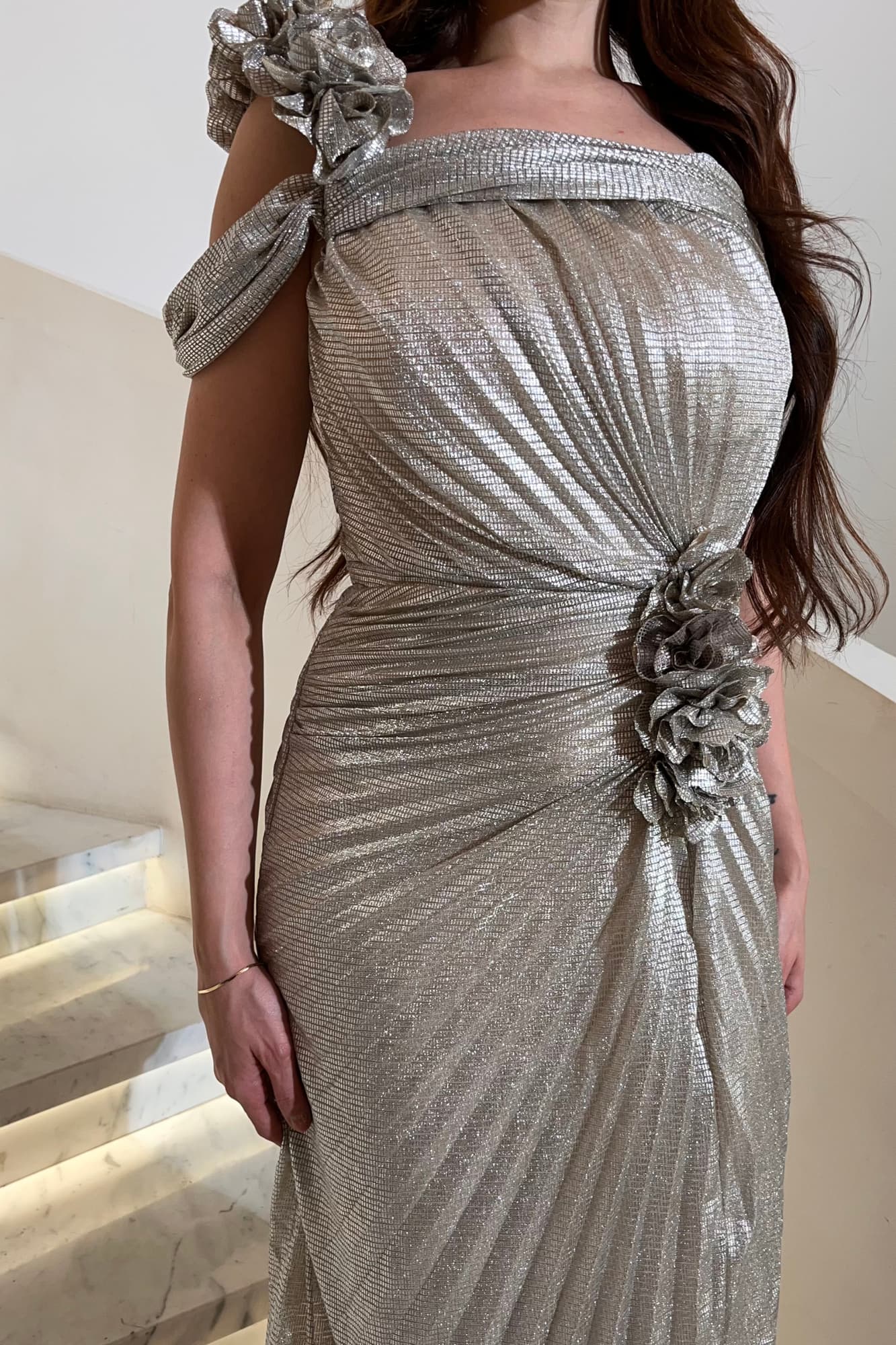 فستان فضّي بتصميم انسيابي يبرز جمال القوام بطريقة راقية من قماش لمّاع مُكسر فضي