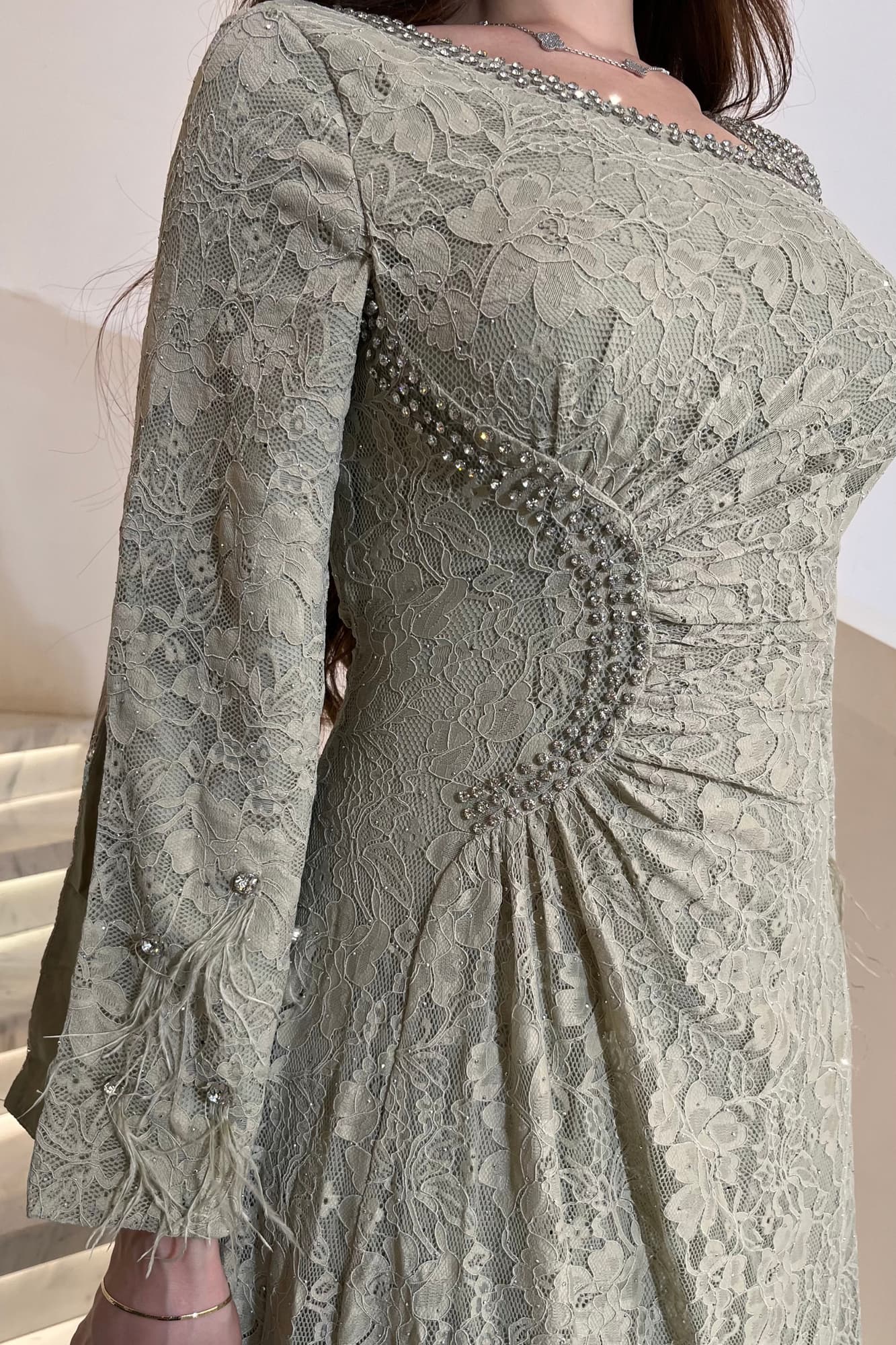 فستان ناعم فخم بتصميم أنثوي راقٍ. مصنوع من دانتيل مطرّز بالكريستالات الفضية عشبي فاتح