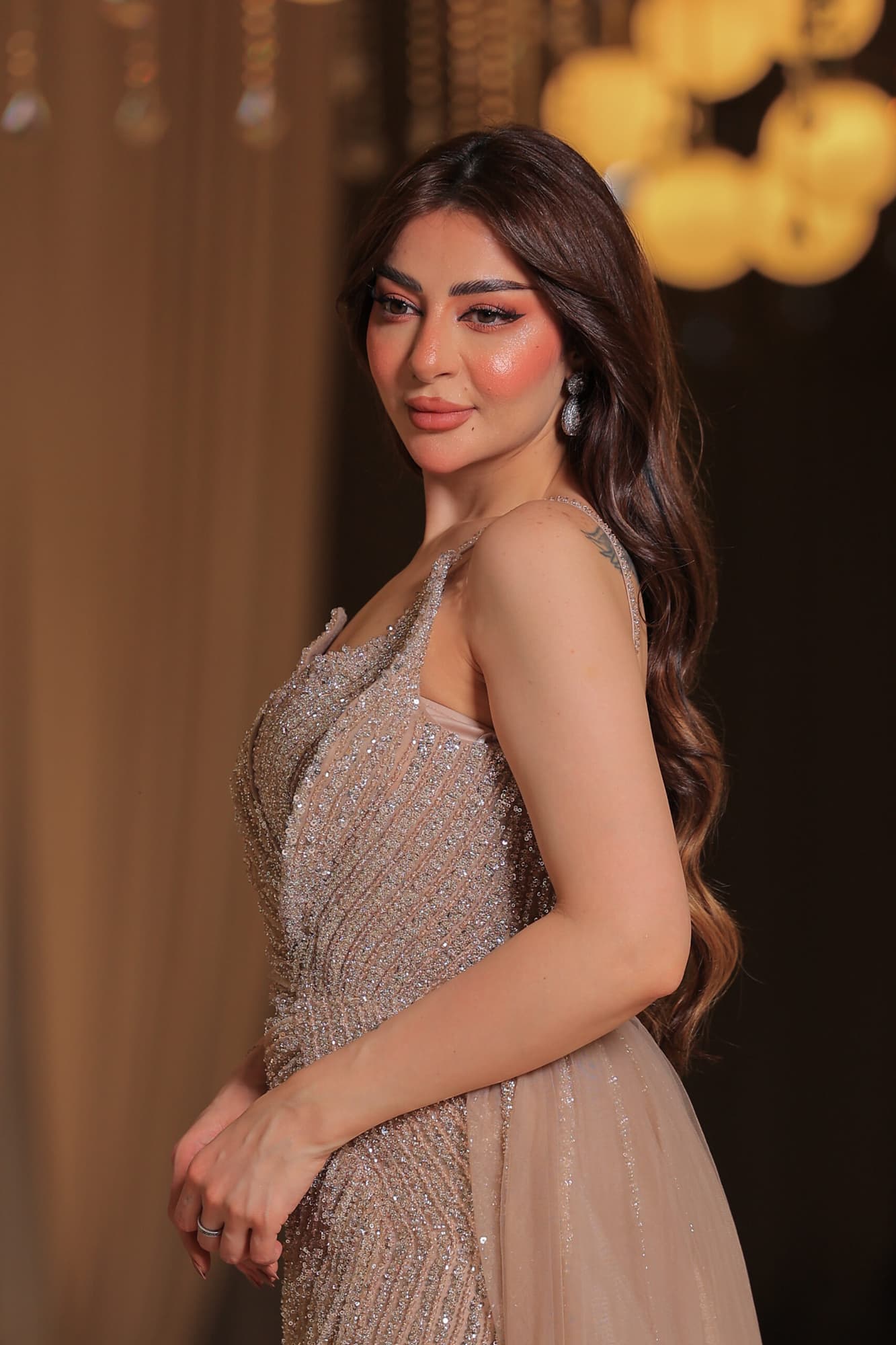 فستان سهرة فاخر بتصميم يُجسد الأناقة يتميز بقماش لامع مرصع بالكامل بالترتر البراق