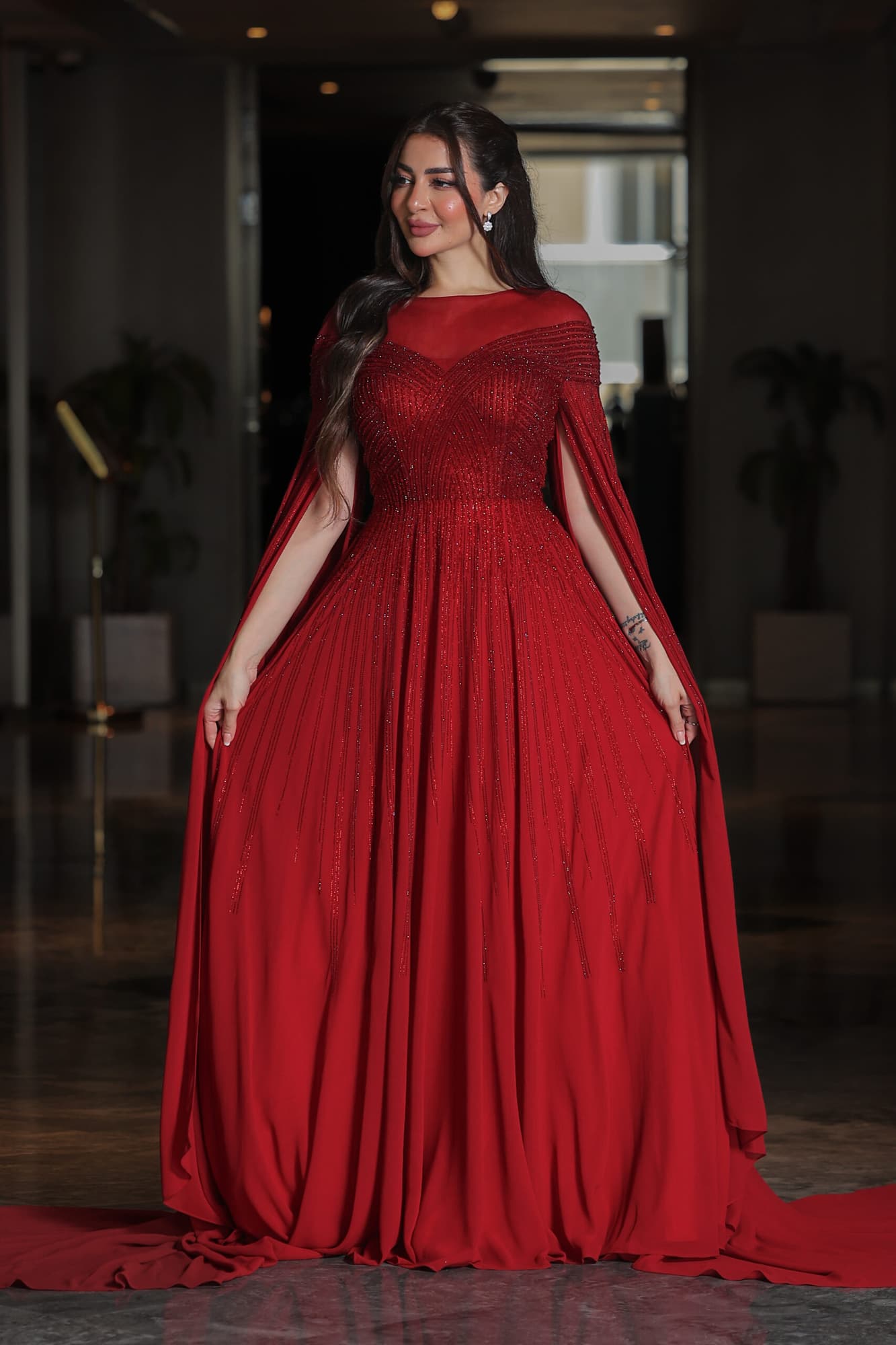 فستان سهرة أنيق مزين بفصوص براقة واكمام كيب احمر