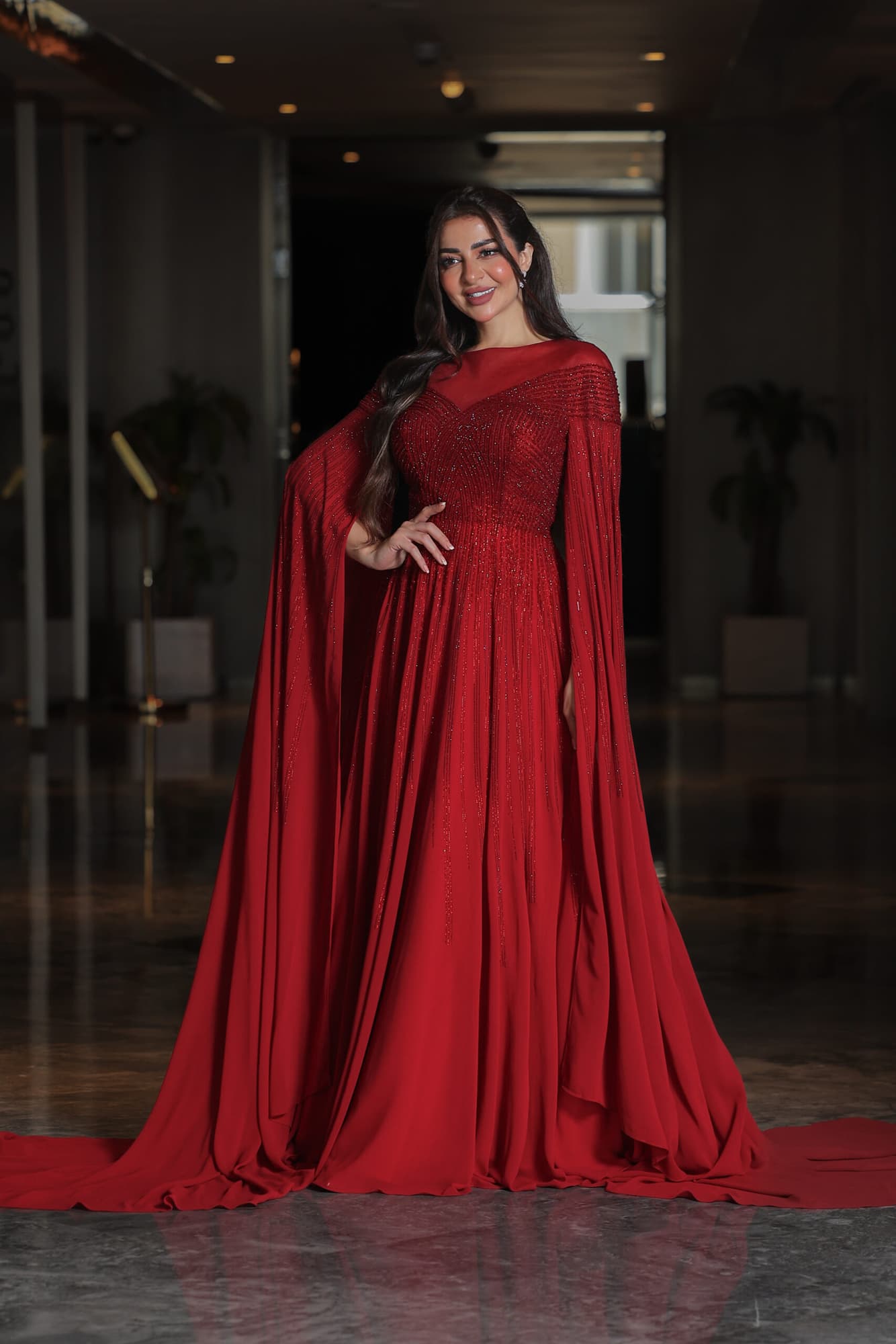 فستان سهرة أنيق مزين بفصوص براقة واكمام كيب