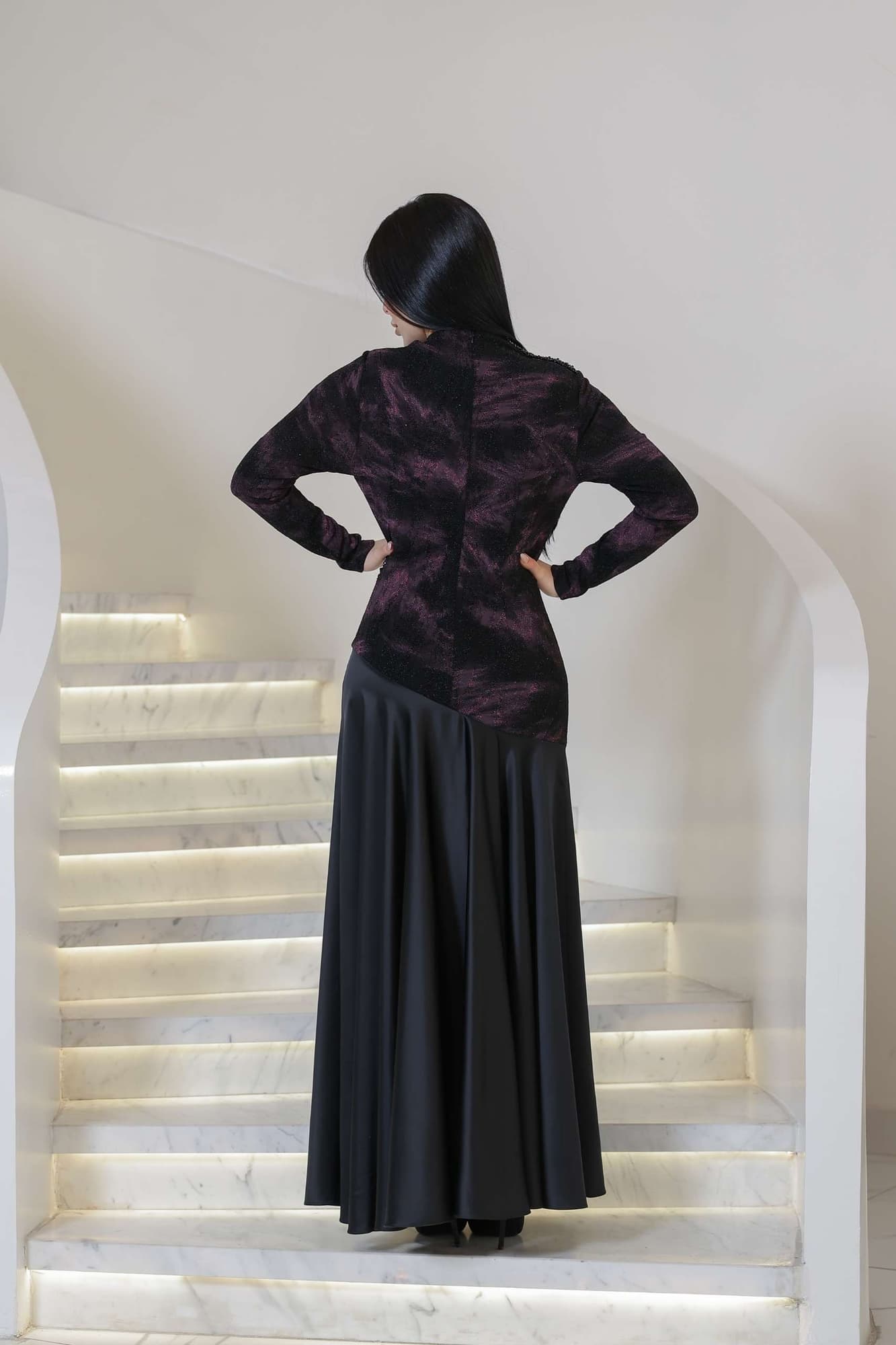 فستان أنيق يجمع بين الغموض والرقي يتميز الجزء العلوي بقماش داكن مع لمعة خفيفة ونقشة فنية