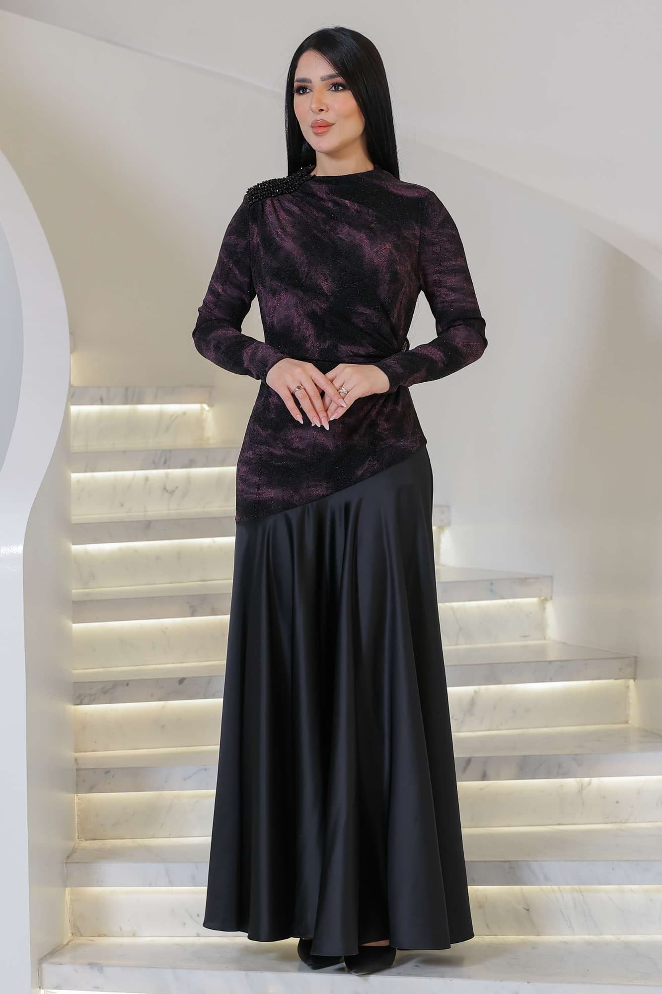 فستان أنيق يجمع بين الغموض والرقي يتميز الجزء العلوي بقماش داكن مع لمعة خفيفة ونقشة فنية