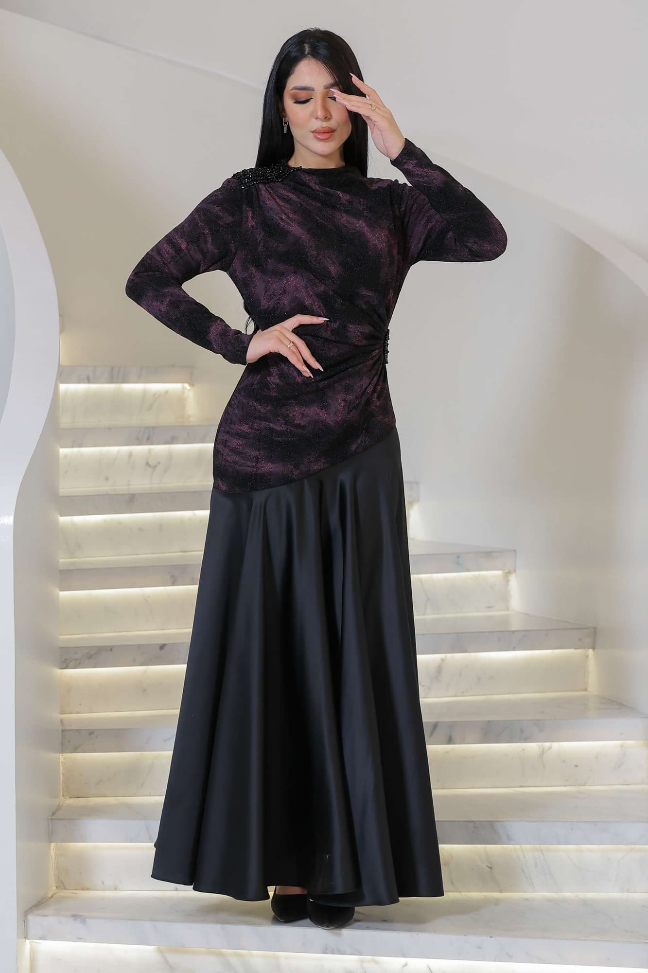 فستان أنيق يجمع بين الغموض والرقي يتميز الجزء العلوي بقماش داكن مع لمعة خفيفة ونقشة فنية