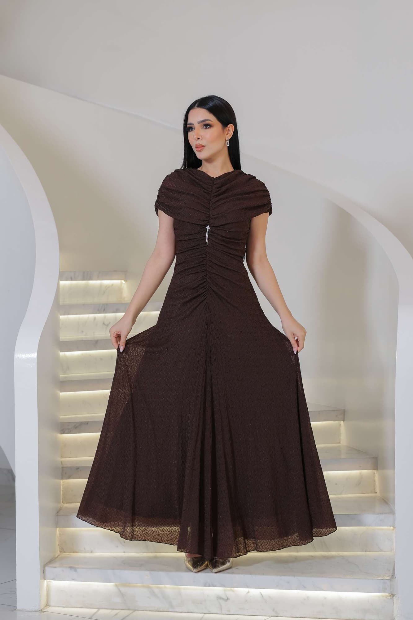 فستان أنيق مزين بفصوص بطول ماكسي بلون بني يتميّز بتصميم ناعم وانسيابي يعكس الرقي والبساطة