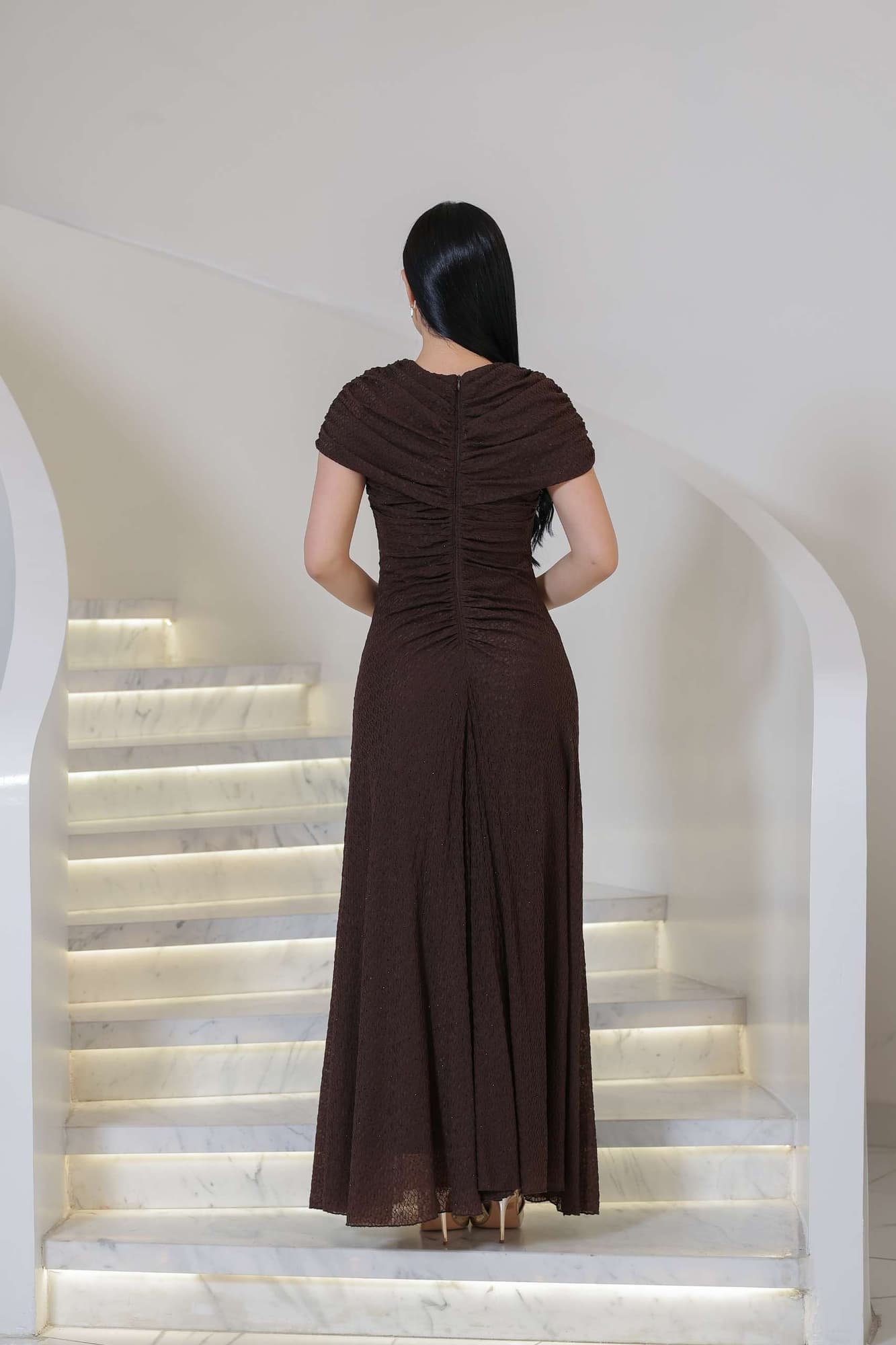 فستان أنيق مزين بفصوص بطول ماكسي بلون بني يتميّز بتصميم ناعم وانسيابي يعكس الرقي والبساطة