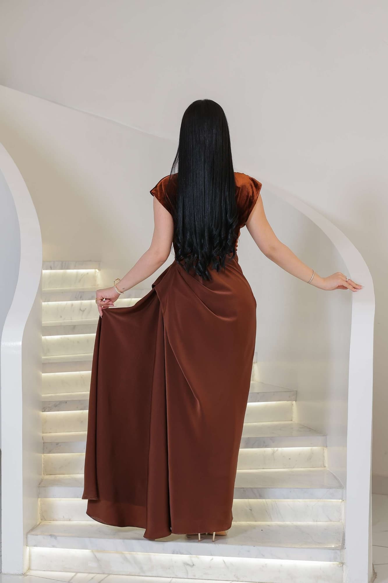 فستان يجمع بين نعومة المخمل في الجزء العلوي وانسيابية قماش الساتان في الاسفل ليخلق تباينًا غنيًا بالفخامة والأنوثة.