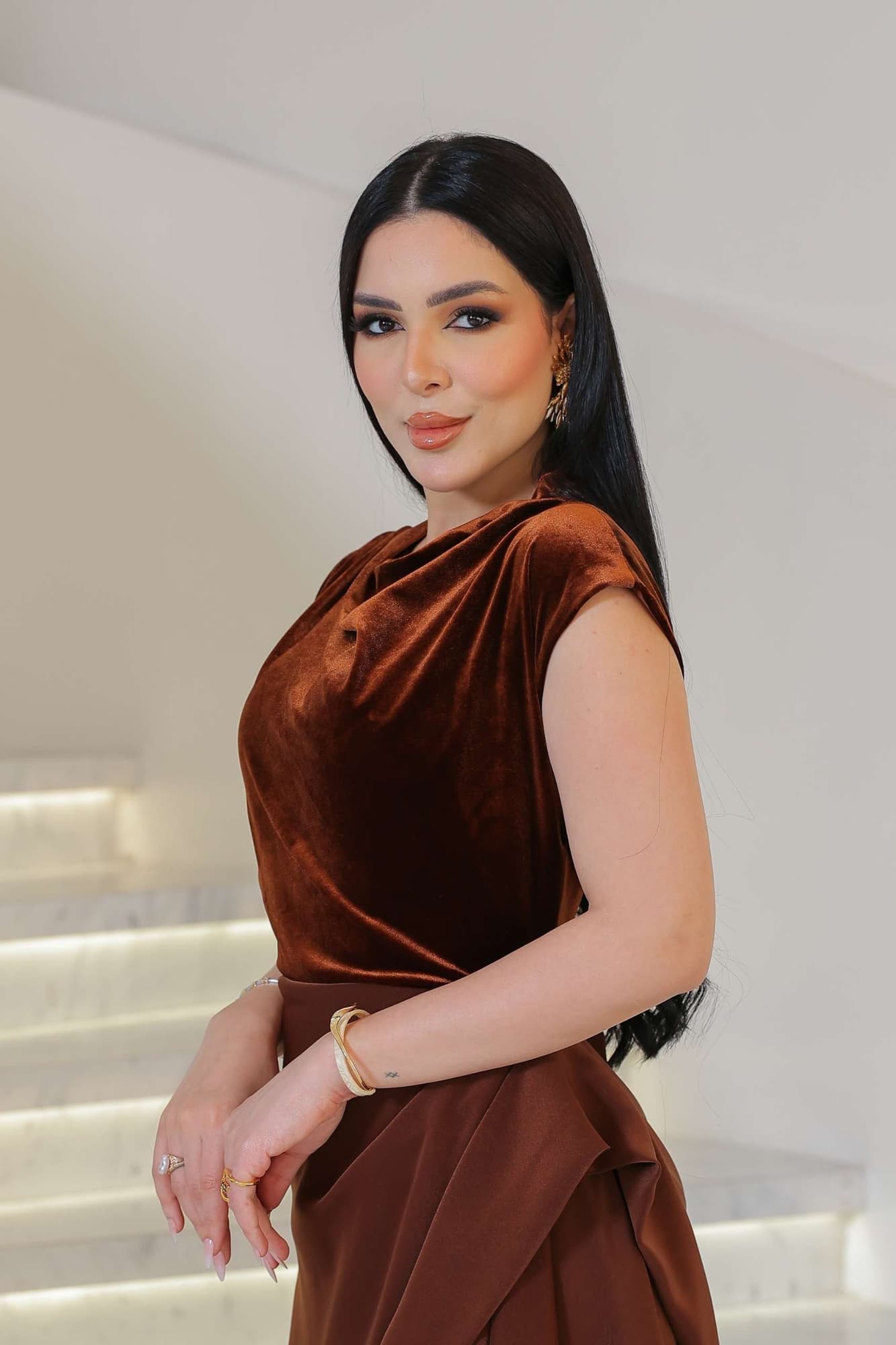 فستان يجمع بين نعومة المخمل في الجزء العلوي وانسيابية قماش الساتان في الاسفل ليخلق تباينًا غنيًا بالفخامة والأنوثة.