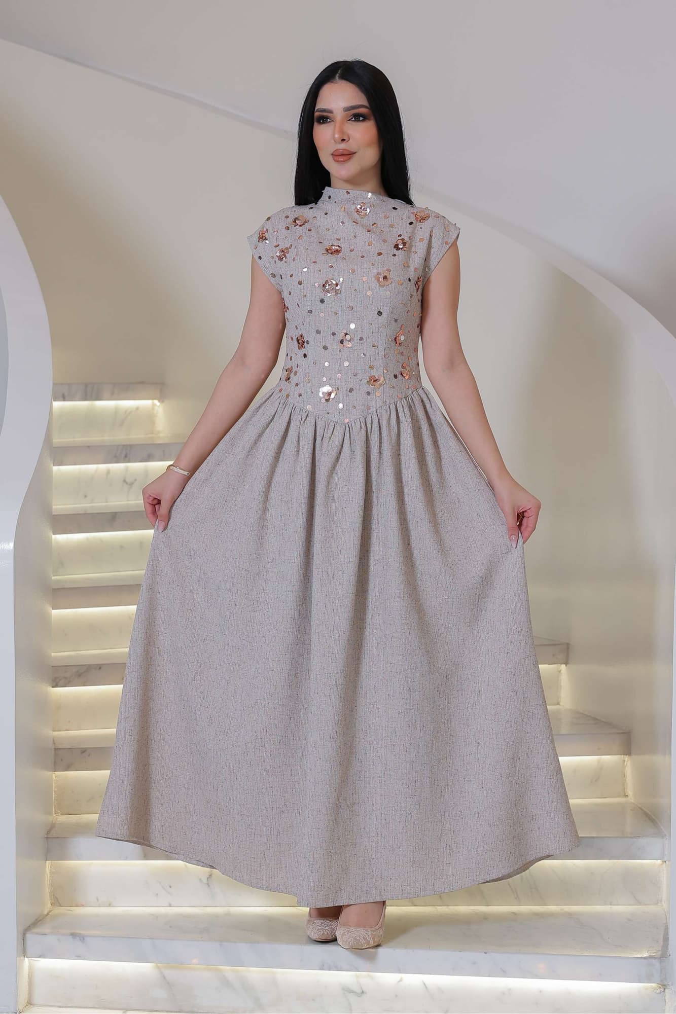 فستان أنيق يجمع بين الرقي الكلاسيكي ولمسة عصرية ناعمة، يتميز بلونه الهادئ ونقوشه اللامعة الرقيقة