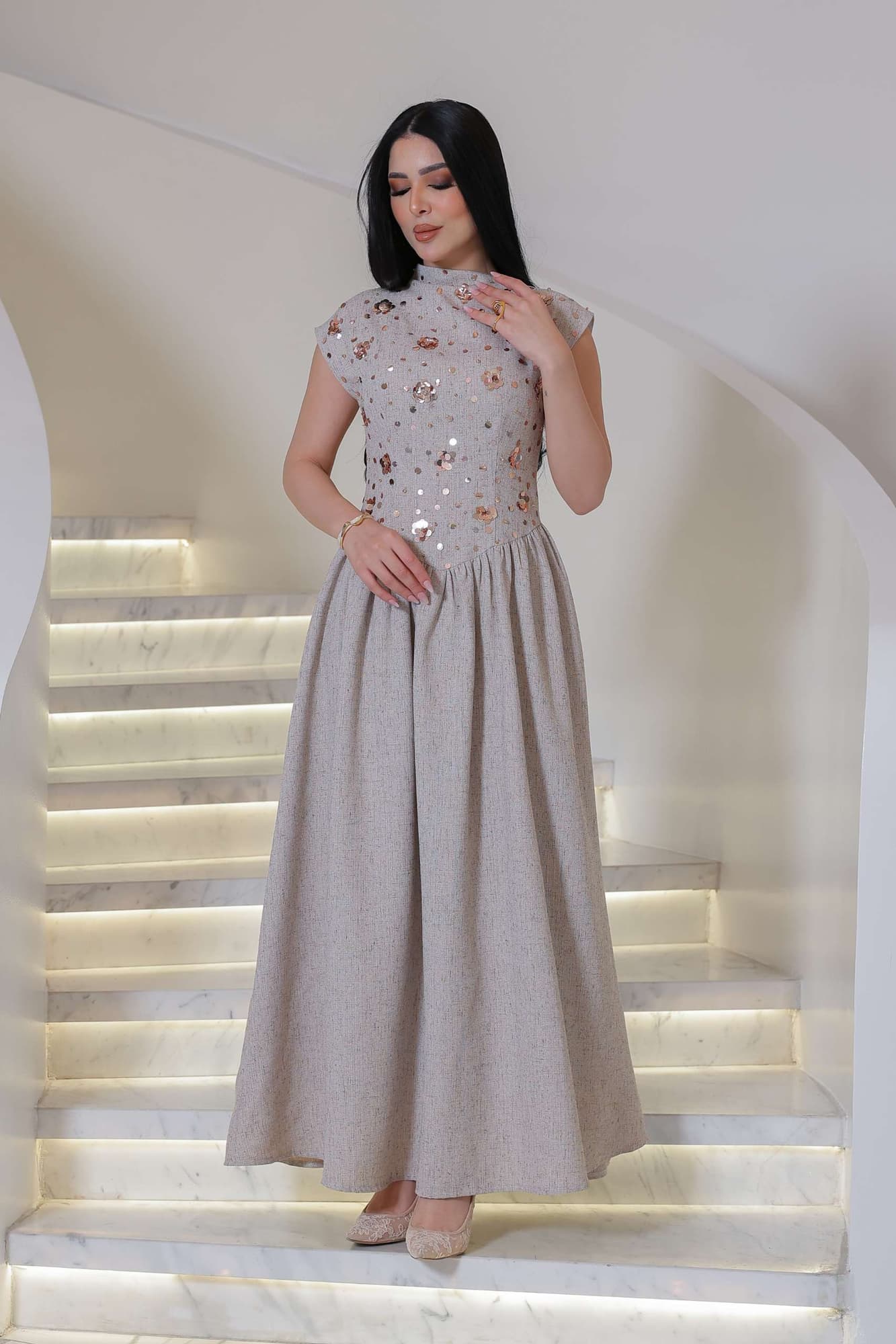 فستان أنيق يجمع بين الرقي الكلاسيكي ولمسة عصرية ناعمة، يتميز بلونه الهادئ ونقوشه اللامعة الرقيقة