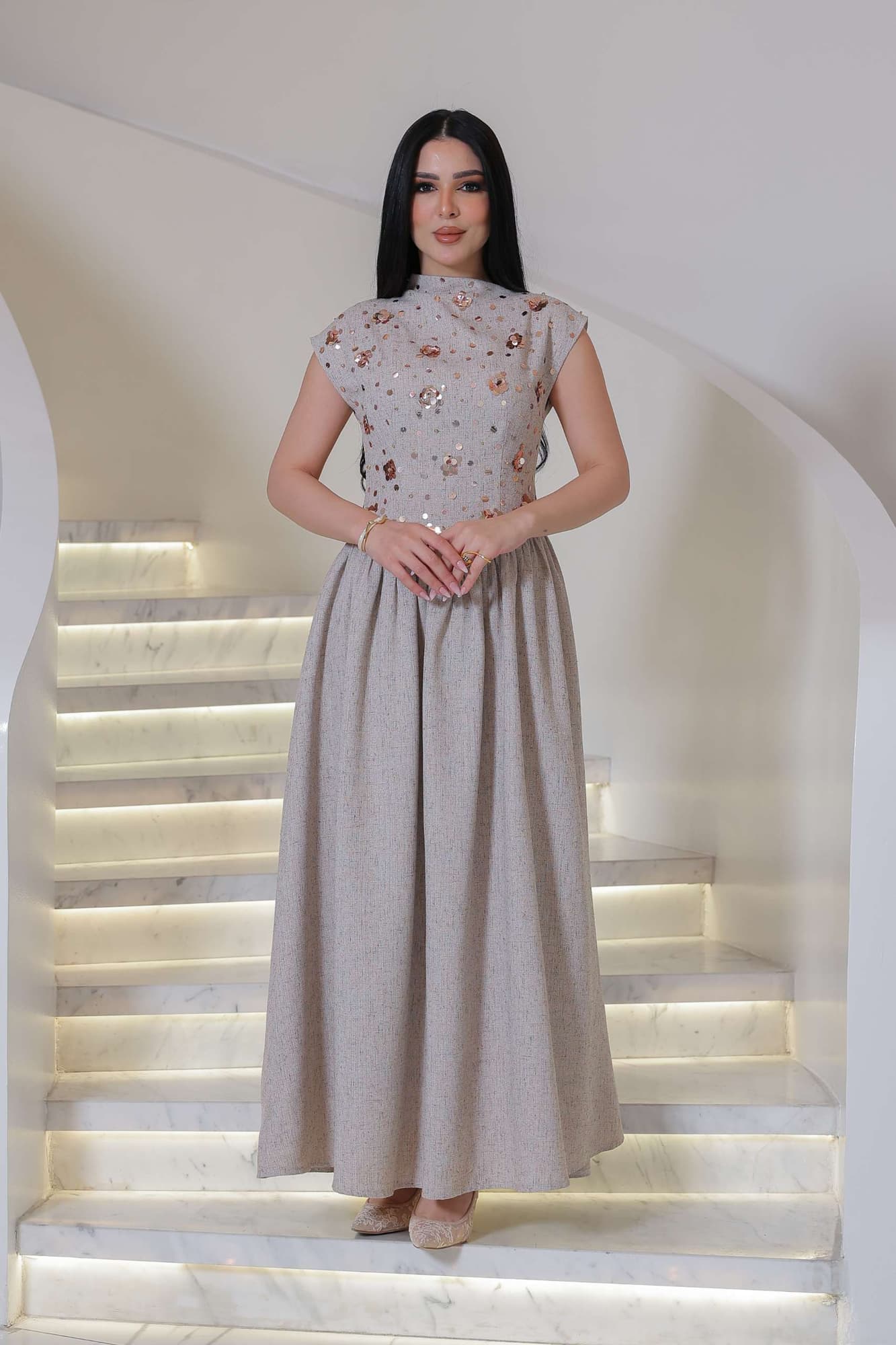 فستان أنيق يجمع بين الرقي الكلاسيكي ولمسة عصرية ناعمة، يتميز بلونه الهادئ ونقوشه اللامعة الرقيقة