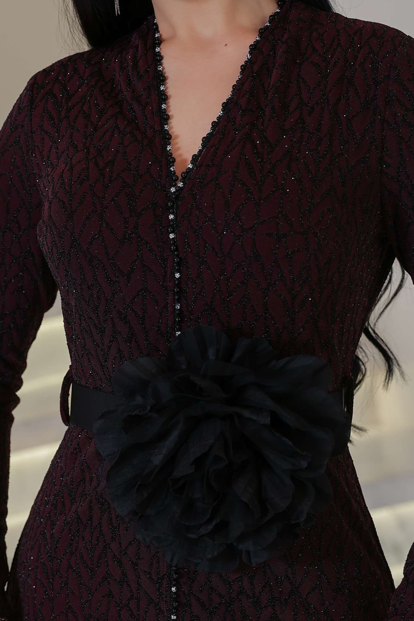 فستان أنيق مصنوع من قماش مطرّز بنقشة ناعمة مزين بتفاصيل دقيقة تمتد طوليًا حتى أسفل الفستان