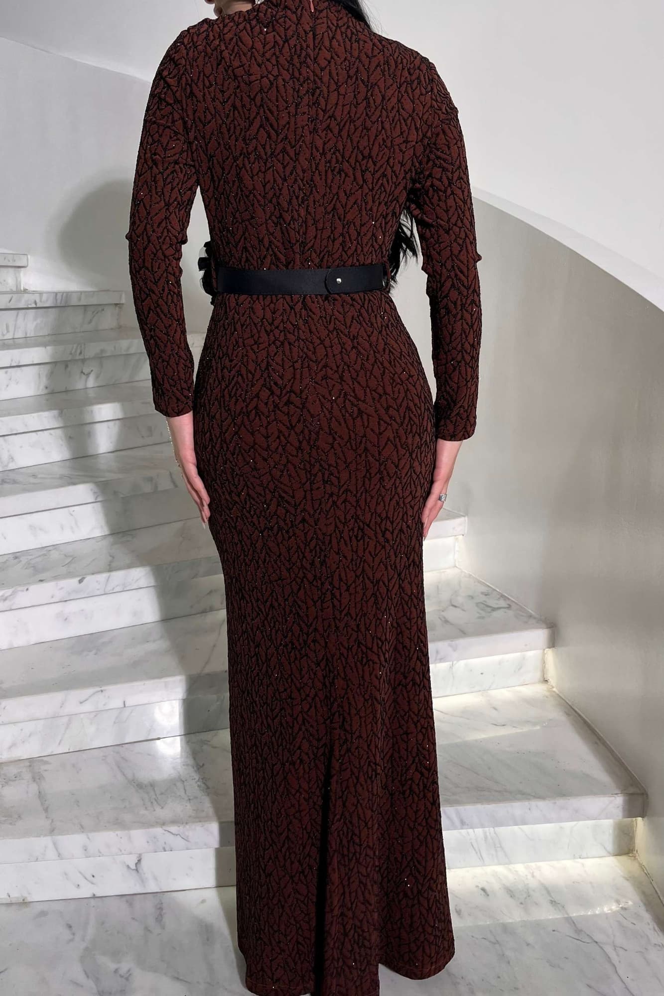 فستان أنيق مصنوع من قماش مطرّز بنقشة ناعمة مزين بتفاصيل دقيقة تمتد طوليًا حتى أسفل الفستان