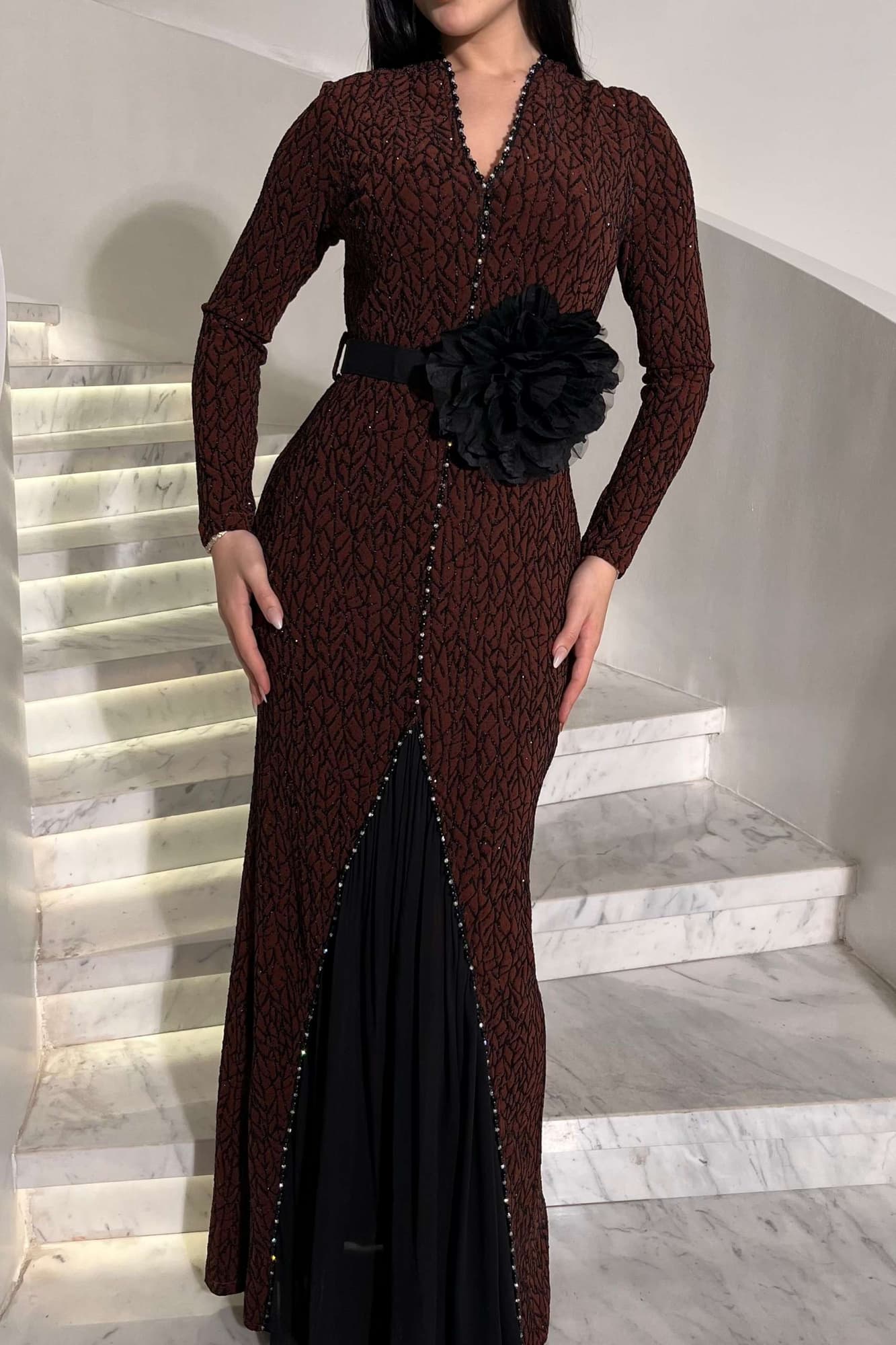 فستان أنيق مصنوع من قماش مطرّز بنقشة ناعمة مزين بتفاصيل دقيقة تمتد طوليًا حتى أسفل الفستان