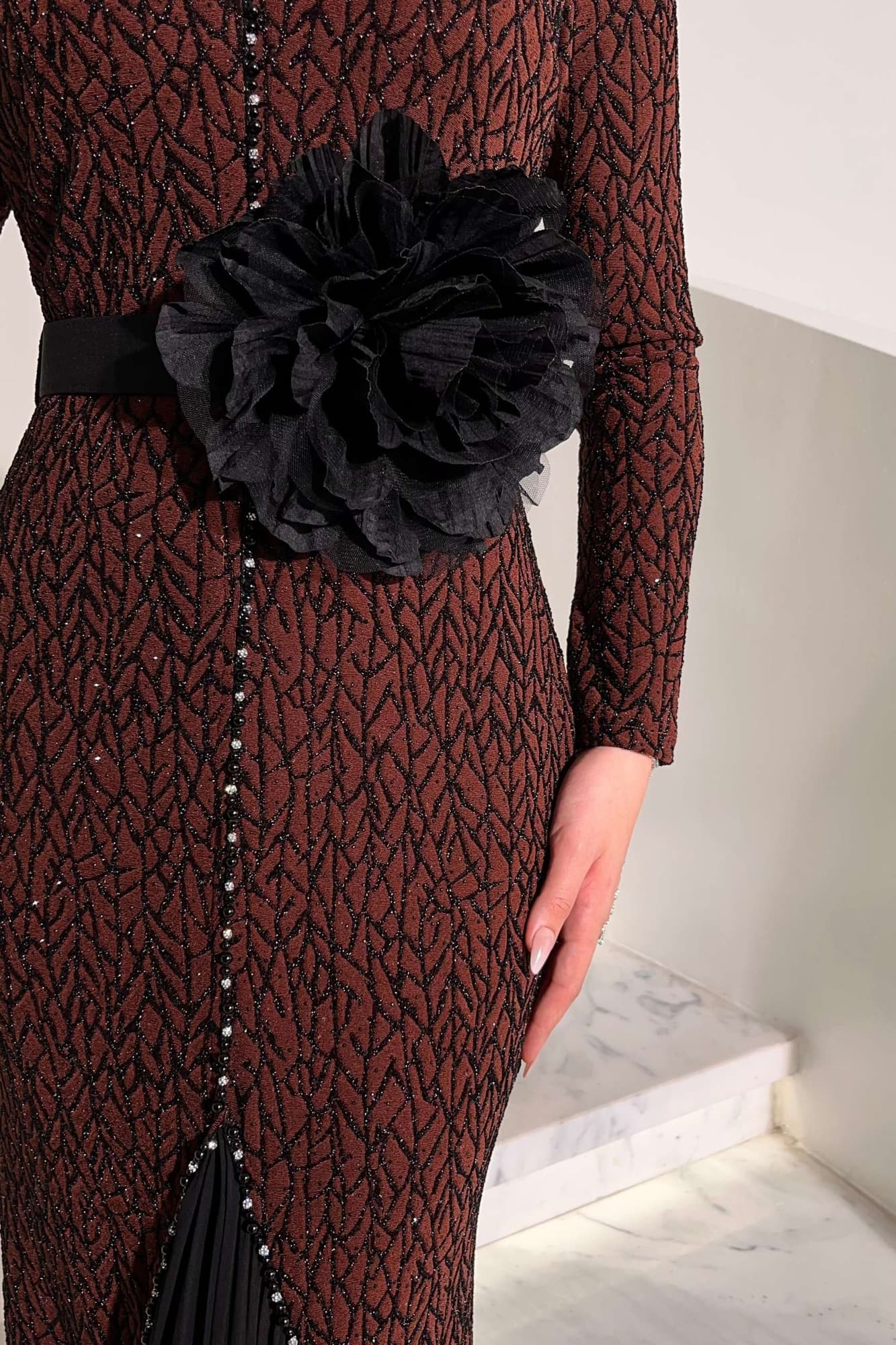 فستان أنيق مصنوع من قماش مطرّز بنقشة ناعمة مزين بتفاصيل دقيقة تمتد طوليًا حتى أسفل الفستان