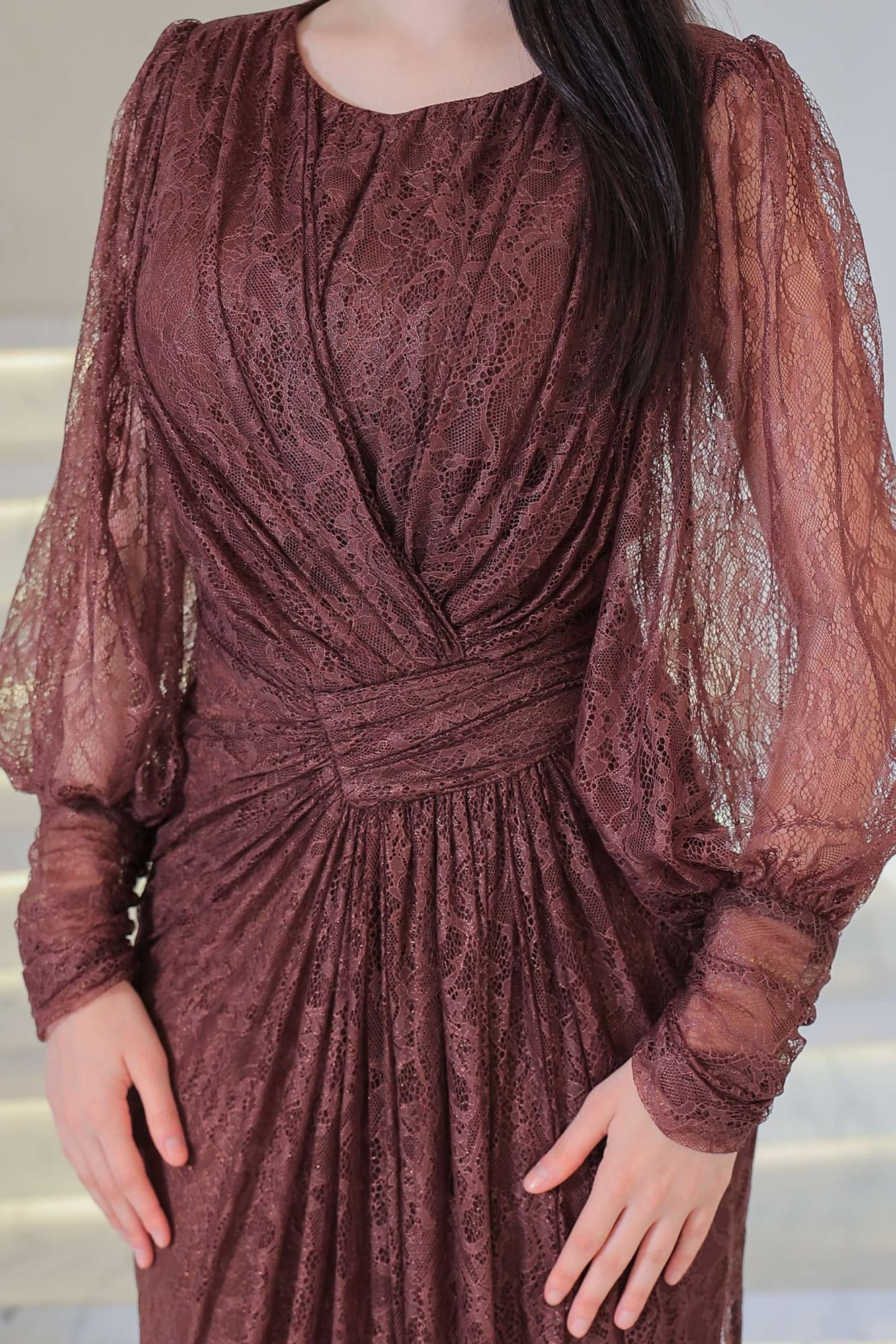 فستان دانتيل طويل يتميز بتفاصيل draping ملتفة حول منطقة الخصر تنحت الجسم بأسلوب أنثوي