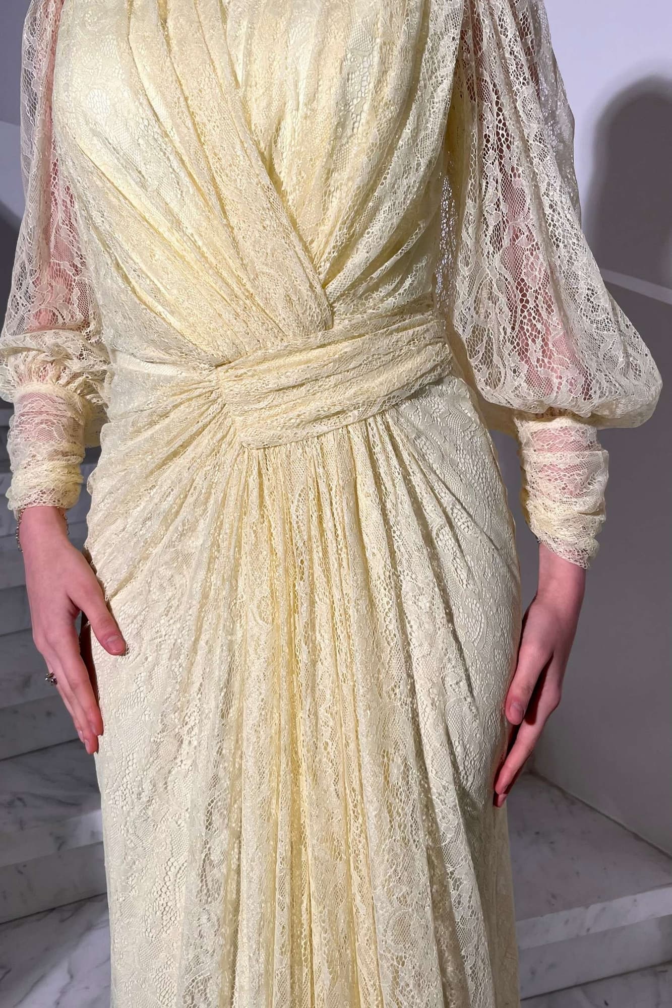 فستان دانتيل طويل يتميز بتفاصيل draping ملتفة حول منطقة الخصر تنحت الجسم بأسلوب أنثوي