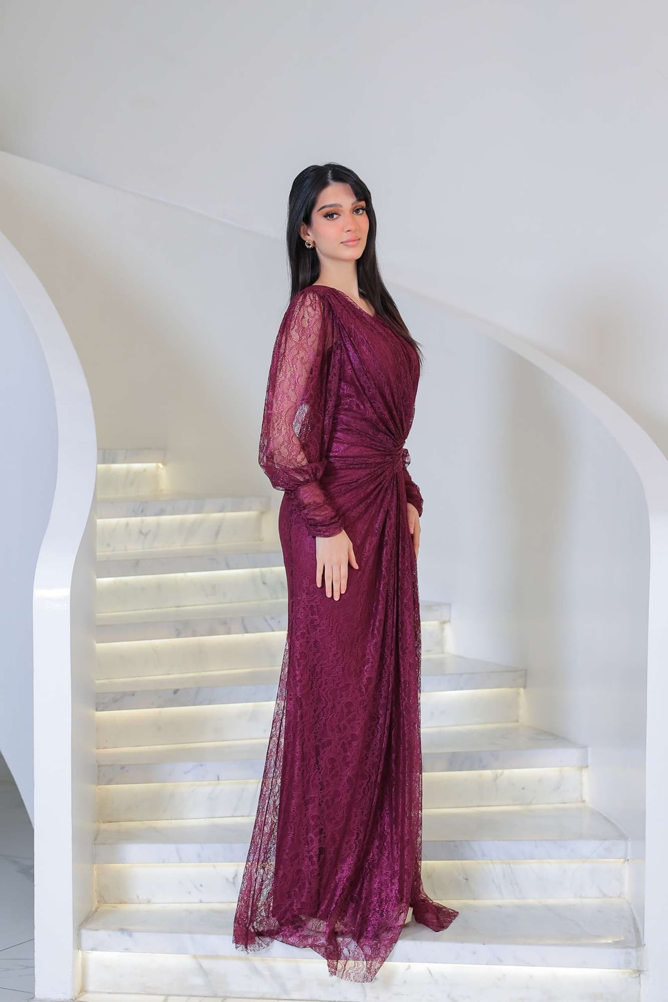 فستان دانتيل طويل يتميز بتفاصيل draping ملتفة حول منطقة الخصر تنحت الجسم بأسلوب أنثوي